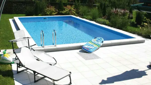 Ein **Holzpool selber bauen ohne Bausatz** ist möglich! Hier ist ein fertiger Pool mit Liegestühlen und aufblasbarem Spielzeug im Garten.